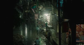Movie still from “All That Breathes” (2022), directed by Shaunak Sen – People are standing on the side of a flooded street; Extreme Wide shot, High angle