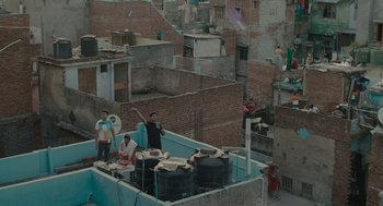 Movie still from “All That Breathes” (2022), directed by Shaunak Sen – A group of people standing on top of a building; Extreme Wide shot, High angle