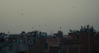Movie still from “All That Breathes” (2022), directed by Shaunak Sen – Kites are flying in the sky over a city; Extreme Wide shot, Low angle
