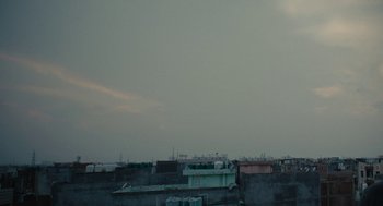 Movie still from “All That Breathes” (2022), directed by Shaunak Sen – A view of the sky from a roof top; Extreme Wide shot, Low angle