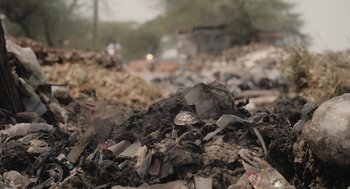 Movie still from “All That Breathes” (2022), directed by Shaunak Sen – A large pile of trash on the side of a road; Extreme Close Up shot, Low angle