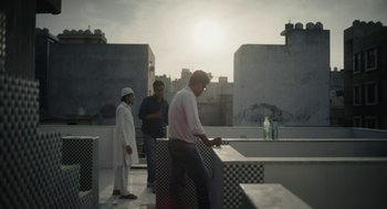 Movie still from “All That Breathes” (2022), directed by Shaunak Sen – A man and two women standing on top of a building; Wide shot, Low angle