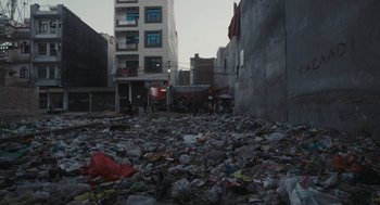 Movie still from “All That Breathes” (2022), directed by Shaunak Sen – A city street filled with trash and garbage; Extreme Wide shot, High angle
