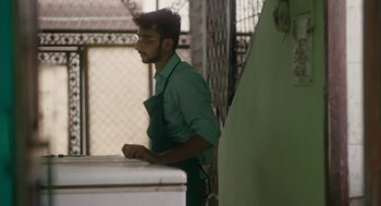 Movie still from “All That Breathes” (2022), directed by Shaunak Sen – A man in a green shirt and a green apron; Medium shot, Low angle