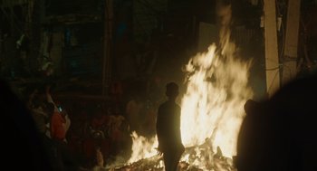 Movie still from “All That Breathes” (2022), directed by Shaunak Sen – A man standing in front of a fire; Wide shot, High angle