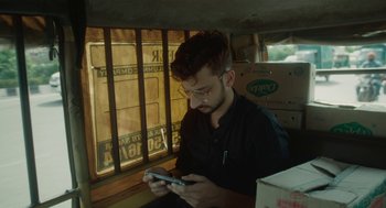 Movie still from “All That Breathes” (2022), directed by Shaunak Sen – A man sitting in a car looking at his cell phone; Close Up shot, Low angle