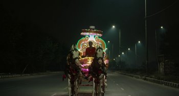 Movie still from “All That Breathes” (2022), directed by Shaunak Sen – A horse drawn carriage with a man on the back of it; Extreme Wide shot, Low angle