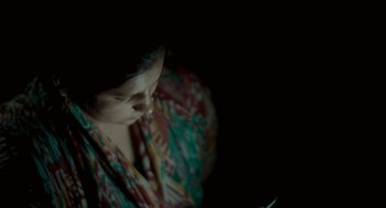 Movie still from “All That Breathes” (2022), directed by Shaunak Sen – A woman is looking at her cell phone in the dark; Close Up shot, High angle