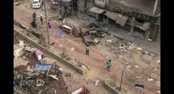 Movie still from “All That Breathes” (2022), directed by Shaunak Sen – Two people standing on the side of the street; Extreme Wide shot, High angle