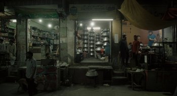 Movie still from “All That Breathes” (2022), directed by Shaunak Sen – A store with a bunch of pots on the wall; Wide shot, High angle