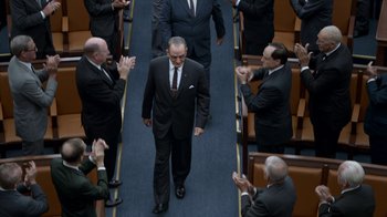 Movie still from “All the Way” (2016), directed by Jay Roach – A group of men in suits are applauding a man; Wide shot, Low angle