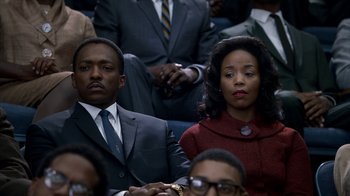 Movie still from “All the Way” (2016), directed by Jay Roach – A man and a woman sitting in a crowd of people; Medium shot, Over the shoulder angle