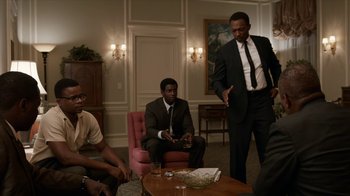 Movie still from “All the Way” (2016), directed by Jay Roach – A group of men in suits and ties in a living room; Medium shot, Over the shoulder angle