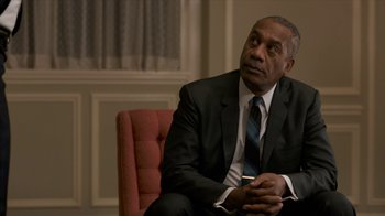Movie still from “All the Way” (2016), directed by Jay Roach – A man in a suit sitting in a red chair; Close Up shot, Over the shoulder angle