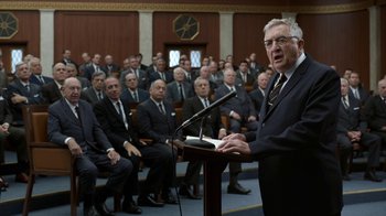 Movie still from “All the Way” (2016), directed by Jay Roach – An older man is speaking at a podium in front of a group of men; Medium shot, Over the shoulder angle