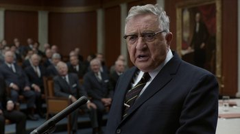 Movie still from “All the Way” (2016), directed by Jay Roach – An older man in a suit and tie speaking into a microphone in front of a group of older men; Close Up shot, Over the shoulder angle