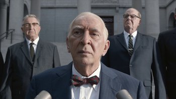 Movie still from “All the Way” (2016), directed by Jay Roach – A man in a suit and a bow tie is standing in front of two other men; Close Up shot, Low angle