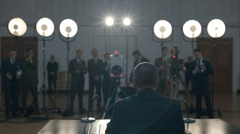 Movie still from “All the Way” (2016), directed by Jay Roach – A group of men in suits are standing in front of microphones; Wide shot, Over the shoulder angle