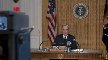 Movie still from “All the Way” (2016), directed by Jay Roach – A man sitting at a table in front of a flag; Medium shot, Low angle