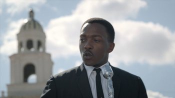 Movie still from “All the Way” (2016), directed by Jay Roach – A man wearing a suit and tie holding a microphone; Close Up shot, Low angle