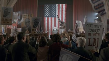 Movie still from “All the Way” (2016), directed by Jay Roach – A group of people in front of an american flag; Wide shot, High angle
