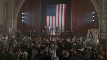 Movie still from “All the Way” (2016), directed by Jay Roach – A crowd of people sitting in front of an american flag; Extreme Wide shot, High angle