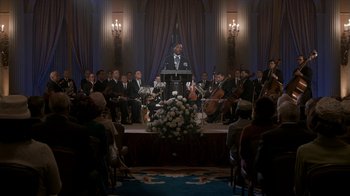 Movie still from “All the Way” (2016), directed by Jay Roach – A group of people sitting in a room with microphones; Extreme Wide shot, Over the shoulder angle