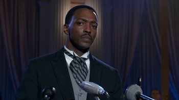 Movie still from “All the Way” (2016), directed by Jay Roach – A man wearing a suit and tie standing in front of microphones; Close Up shot, Over the shoulder angle
