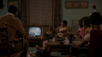 Movie still from “All the Way” (2016), directed by Jay Roach – A group of people sitting in a living room watching tv; Wide shot, High angle
