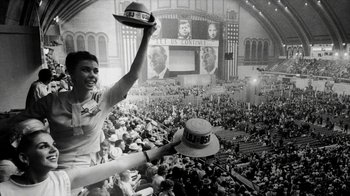 Movie still from “All the Way” (2016), directed by Jay Roach – A man holding a hat in front of a crowd; Wide shot, Low angle