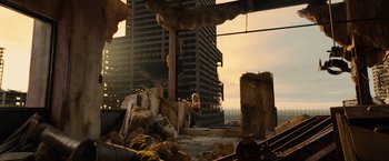 Movie still from “Allegiant” (2016), directed by Robert Schwentke – A woman sitting on a pile of rubble in front of a city skyline; Extreme Wide shot, High angle