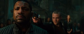 Movie still from “Allegiant” (2016), directed by Robert Schwentke – A man holding a gun in front of another man; Close Up shot, Over the shoulder angle