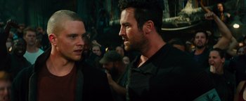 Movie still from “Allegiant” (2016), directed by Robert Schwentke – Two men standing next to each other in front of a crowd of onlookers; Close Up shot, Over the shoulder angle