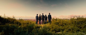 Movie still from “Allegiant” (2016), directed by Robert Schwentke – A group of people standing on top of a grass covered hill; Extreme Wide shot, Low angle