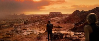 Movie still from “Allegiant” (2016), directed by Robert Schwentke – A man standing on a dirt road looking at the sky; Extreme Wide shot, Low angle