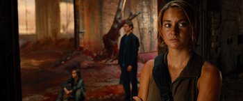 Movie still from “Allegiant” (2016), directed by Robert Schwentke – A group of people standing in a room with blood on the ground; Medium shot, Over the shoulder angle