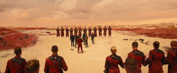 Movie still from “Allegiant” (2016), directed by Robert Schwentke – A group of people standing on top of a sandy beach; Extreme Wide shot, High angle