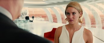 Movie still from “Allegiant” (2016), directed by Robert Schwentke – A woman in a white dress sitting in a room; Close Up shot, Over the shoulder angle