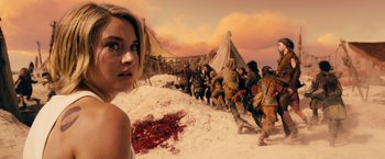 Movie still from “Allegiant” (2016), directed by Robert Schwentke – A woman standing in front of a group of people; Medium shot, Over the shoulder angle