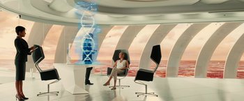Movie still from “Allegiant” (2016), directed by Robert Schwentke – A woman sitting on a chair in a room; Wide shot, Over the shoulder angle