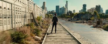 Movie still from “Allegiant” (2016), directed by Robert Schwentke – A man standing on a train track near a body of water; Extreme Wide shot, High angle