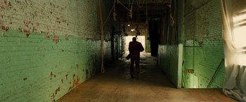 Movie still from “Allegiant” (2016), directed by Robert Schwentke – A man standing in an alley with ropes hanging from the ceiling; Wide shot, High angle