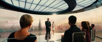 Movie still from “Allegiant” (2016), directed by Robert Schwentke – A group of people standing in front of a large screen; Wide shot, Over the shoulder angle