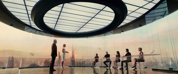 Movie still from “Allegiant” (2016), directed by Robert Schwentke – A group of people sitting around a glass table in a room; Wide shot, Over the shoulder angle