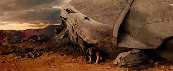Movie still from “Allegiant” (2016), directed by Robert Schwentke – A man is laying on the ground next to an airplane; Wide shot, High angle