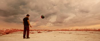 Movie still from “Allegiant” (2016), directed by Robert Schwentke – A person flying a kite on a cloudy day; Extreme Wide shot, High angle