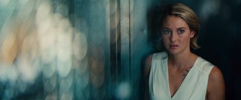 Movie still from “Allegiant” (2016), directed by Robert Schwentke – A woman standing in front of a window with lights; Close Up shot, Over the shoulder angle