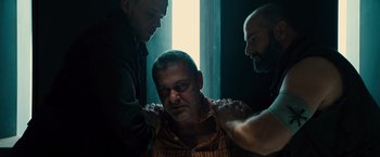 Movie still from “Allegiant” (2016), directed by Robert Schwentke – A man being held down by two other men; Medium shot, Low angle