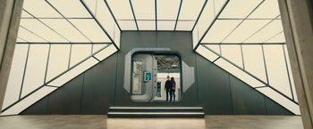 Movie still from “Allegiant” (2016), directed by Robert Schwentke – Two people are standing in front of an open door; Wide shot, Overhead angle