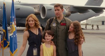 Movie still from “Aloha” (2015), directed by Cameron Crowe – A man and two women and a child standing in front of a plane; Medium shot, Over the shoulder angle
